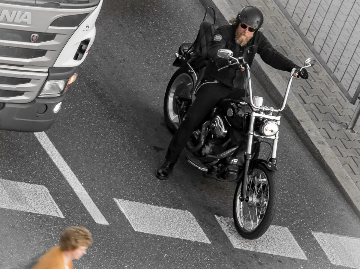 Bearded man on a black motorcycle turning beside a white truck